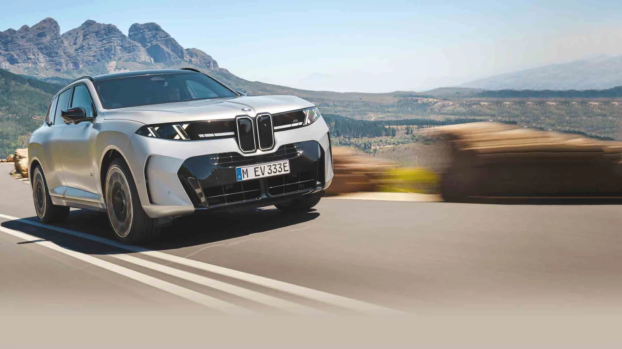 BMW X5 M60e plateado rodando por una carretera de montaña